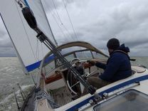 Sailboat heeling under sail in open water with the skipper at the helm