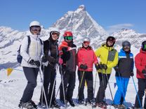 A group of skiers posing on a sunny slope in front of the Matterhorn